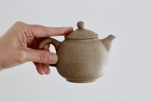 Hand on top of Large Clay Teapot