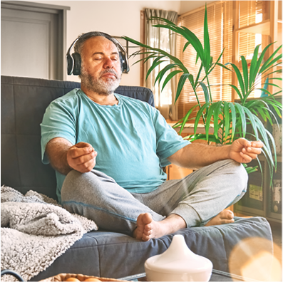 A man is meditating on a couch with headphones on.