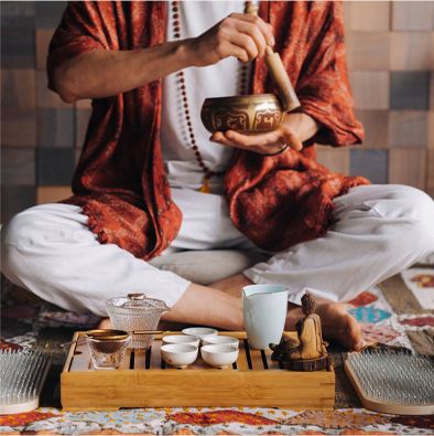 A man in a red robe is holding a bowl of tea.